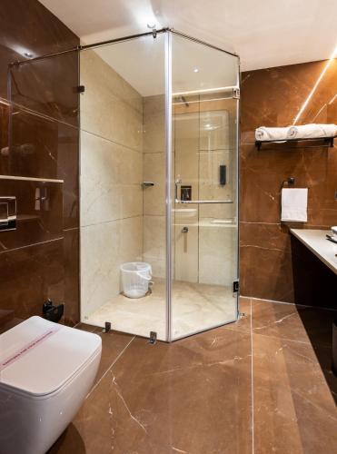 a bathroom with a shower with a toilet and a sink at AIRA Boutique Hotel in Bangalore