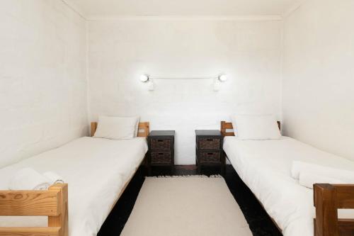 two twin beds in a room with white walls at Lumberjack Cottage at Blombosch Game Farm in Yzerfontein