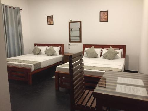 a room with two beds and a bench in it at Mimi's Cottage in Udawalawe