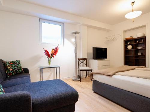 a bedroom with a bed and a couch and a tv at Beim Thöny - schönes Apartment mit privatem Zugang in Utting am Ammersee