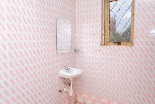 a pink bathroom with a sink and a mirror at Admiral Hotel and Spa Kampala in Kampala