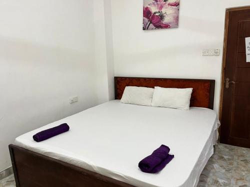 a bed with two purple pillows on top of it at BeachBay Guest House in Negombo
