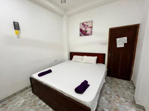 a small bedroom with a white bed with a purple object on it at BeachBay Guest House in Negombo