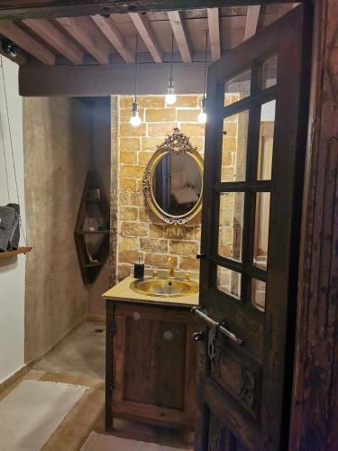 a bathroom with a sink and a mirror on a brick wall at chambres d'hôtes l'atrium in Orange