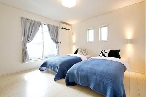 a bedroom with two beds with blue and white blankets at Maison Haan Motobu in Motobu
