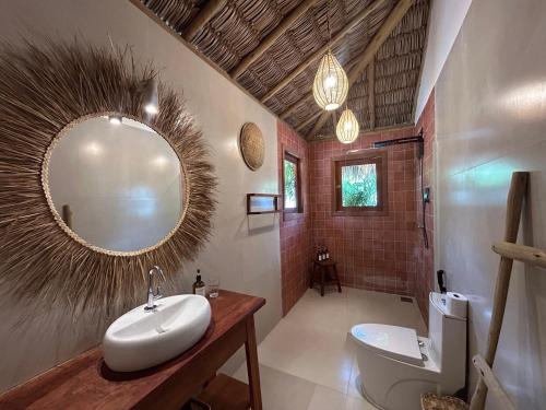 a bathroom with a sink and a toilet and a mirror at Tiki Pool's Bungalows in Fortim