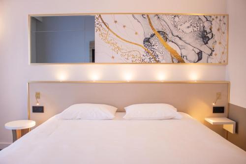 a bedroom with a white bed with lights above it at Brit Hotel Cahors Centre - Le Valentre in Cahors