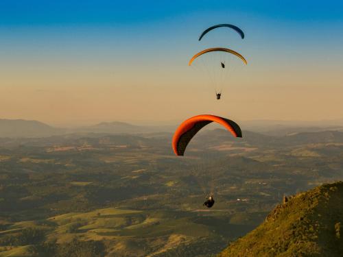 two paragliders flying in the sky over a valley at Living in Poços de Caldas