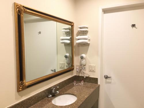 a bathroom with a sink and a mirror and towels at Simply Home Inn & Suites - Riverside in Riverside