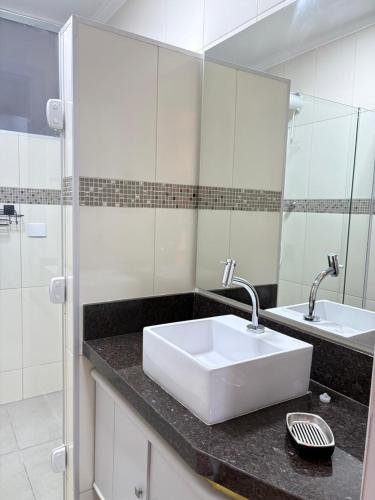 a bathroom with a white sink and a mirror at Dias Felizes - Apto Centro Serra Negra - Edifício Cisne in Serra Negra