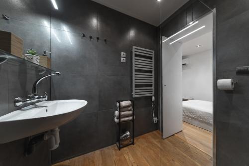 a bathroom with a sink and a mirror and a bed at Apartmán Daniel in Levoča