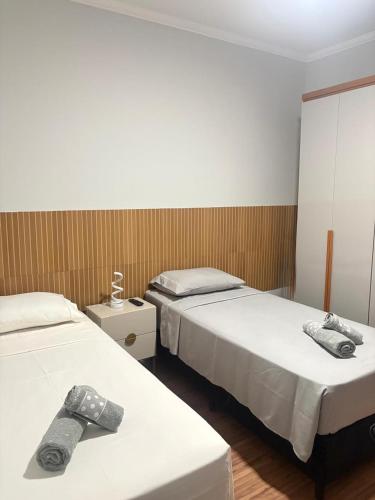 two beds in a hotel room with towels on them at Dias Felizes - Apto Centro Serra Negra - Edifício Cisne in Serra Negra