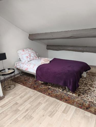 a bedroom with a purple bed and a table at Le Nid Daudèce in Le Châtelet-sur-Sormonne