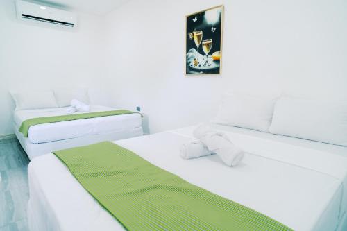 two beds in a white room with a picture on the wall at Green Lodging House in Anda