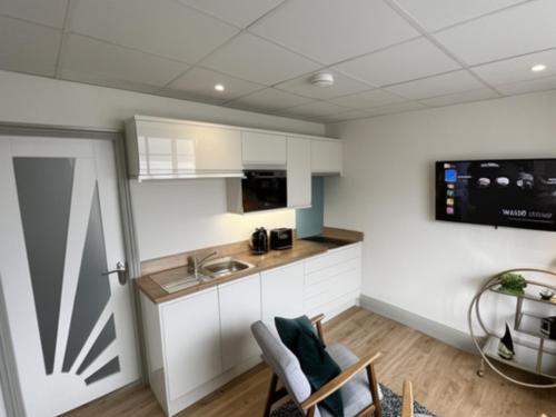 a kitchen with white cabinets and a sink at Sunray Suites in Barmouth