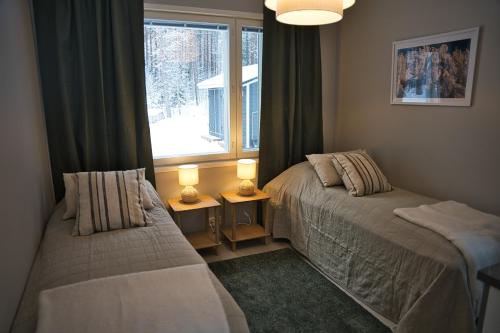 a bedroom with two beds next to a window at Villa Rantakukka Koli, oma ranta in Kolinkylä