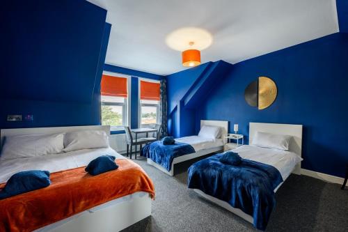two beds in a room with blue walls at Spacious Central Nottingham House in Nottingham