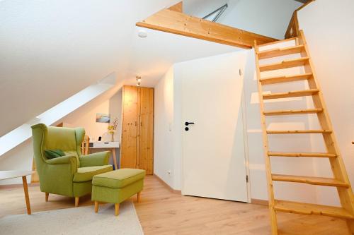 una stanza con una sedia verde e una scala di Ferienhaus Dörte a Hohwacht