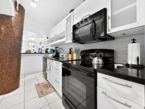 a kitchen with white cabinets and a black stove top oven at Miami Beach Studio with shared Heated Pool & Gym in Miami Beach