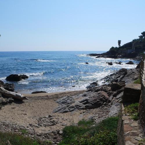 a beach with rocks and the ocean on a sunny day at Villa Perle De La Mer in Saint-Aygulf