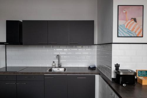 a kitchen with black cabinets and a sink at BBgebouw39 - op de Rijkswerf in Den Helder