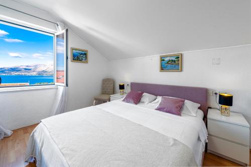 a white bedroom with a large bed and a window at Villa Nick in Cavtat