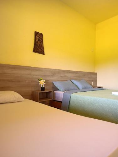 two beds in a hotel room with yellow walls at Pousada Chales da Canastra in Vargem Bonita