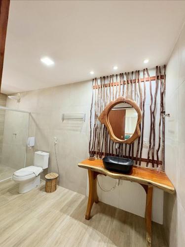 a bathroom with a sink and a toilet and a mirror at Pousada Corais do Bitingui in Japaratinga