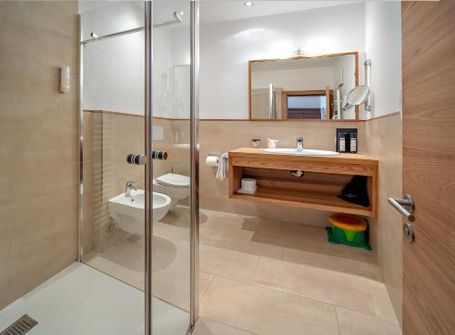 a bathroom with a shower and a toilet and a sink at Family Hotel Posta in Santa Cristina Gherdëina