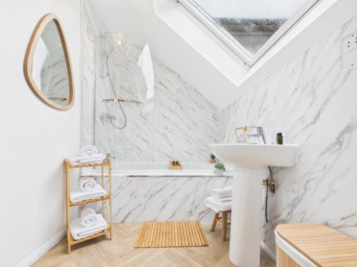 a white bathroom with a sink and a bath tub at The Bridge View Apartment in Hawick