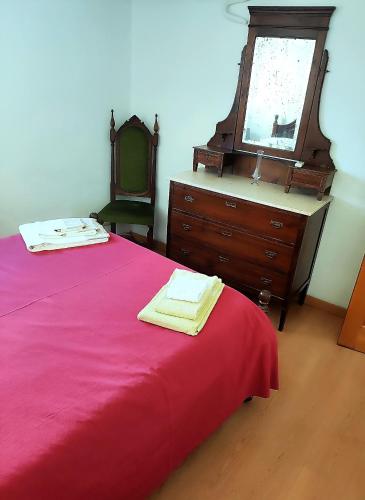 a bedroom with a red bed with a dresser and a mirror at Casa da Avó Maria in Podence