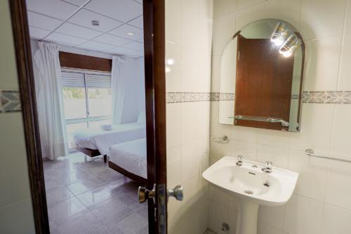 a bathroom with a sink and a bed and a mirror at Residencial Campo-Mar by Umbral in Portimão