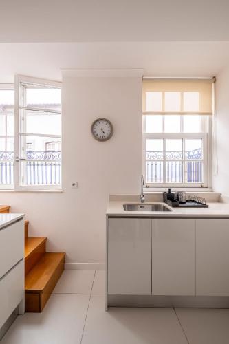 a kitchen with white cabinets and a clock on the wall at Terro Collection - Anjo in Braga