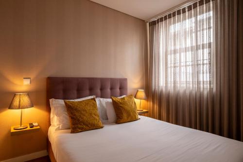 a bedroom with a bed with two lamps and a window at Terro Collection - Anjo in Braga