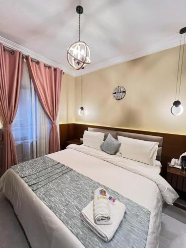 a bedroom with a large white bed and a chandelier at Hotel de l'Air in Douala