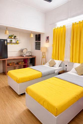 two beds in a room with yellow curtains at Elite Hostel- SB Road Pune in Pune