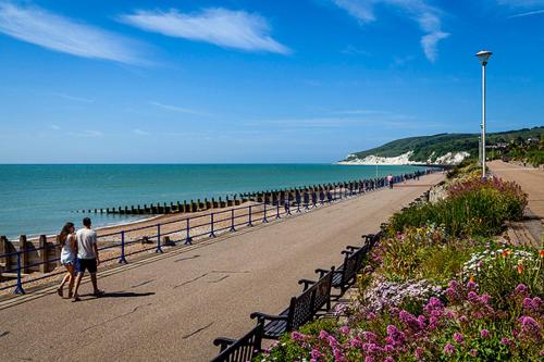 two people walking on a beach near the ocean at East Beach Hotel in Eastbourne