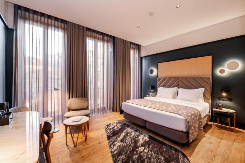 a hotel room with a bed and a chair at Axis Porto Club Aliados in Porto