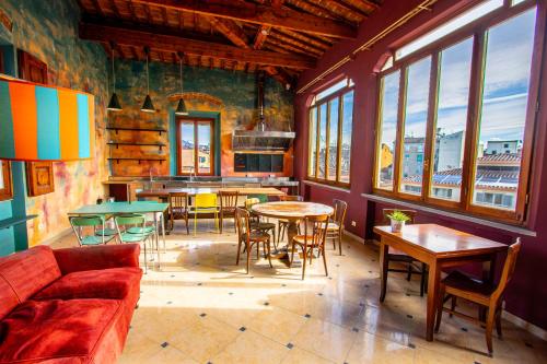 a living room with tables and chairs and windows at Ostello Bello Firenze in Florence