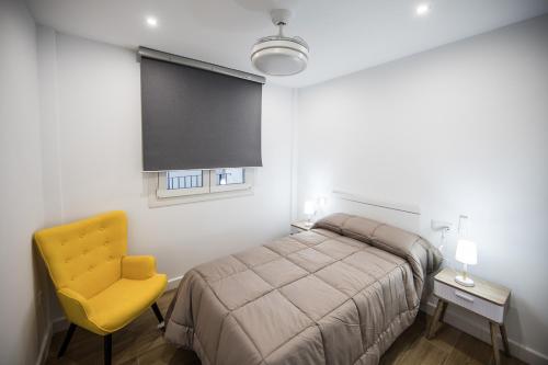 a bedroom with a bed and a yellow chair at Apartamentos Ciudad del Cava in Almendralejo