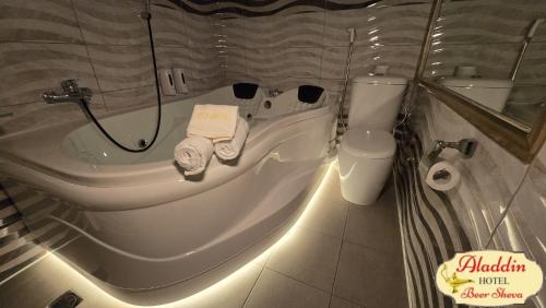 a bathroom with a bath tub and a toilet at Aladdin Hotel Beer Sheva in Beer Sheva