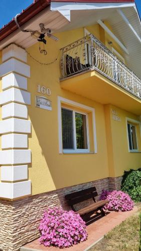 a yellow house with a balcony and a bench at Vila Adria in Hrabušice