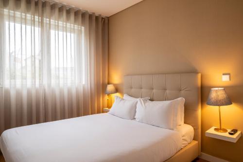 a bedroom with a large white bed and a window at Terro Collection - Anjo in Braga