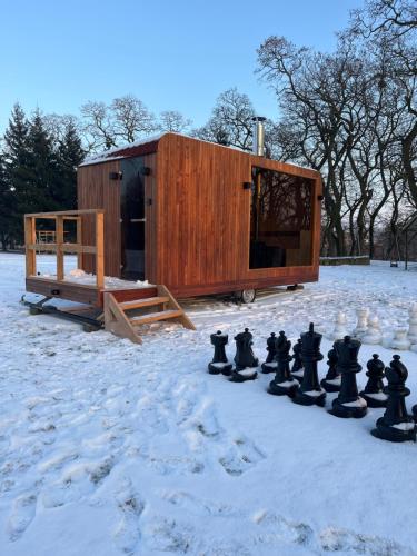 una piccola casa di legno con una scacchiera nella neve di Dworek Biesiadny a Radzewice