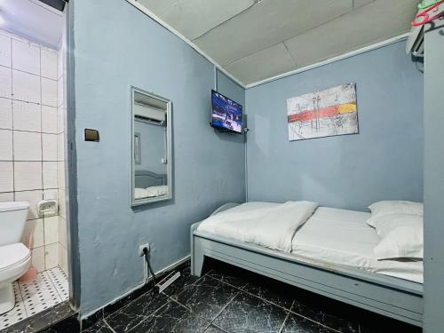 a small blue room with a bed and a sink at CAMERHOME Carrefour mosqué Cité des palmiers in Douala