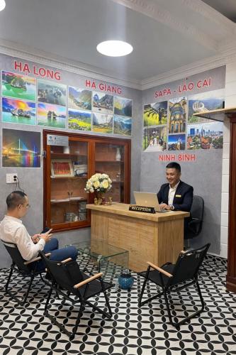 two men sitting in chairs at a desk with a laptop at Hotel Hc Luxury Apartment in Hanoi
