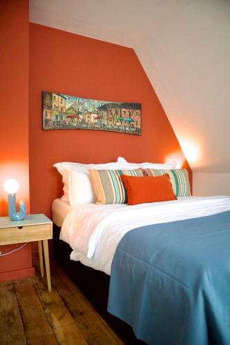 a bedroom with an orange wall with a bed and a table at Haus-Selma in Lüneburg