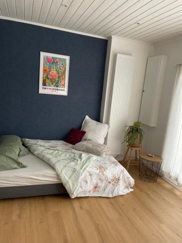 a bedroom with a bed with a blue wall at Coquelicot in Waulsort