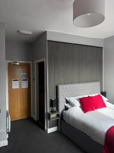 a bedroom with a large bed with red pillows at Feildens Arms Hotel in Blackburn