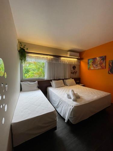 two beds in a room with orange walls at Suíte aconchegante beira mar - Suíte 255 in Guarujá